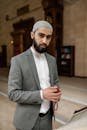 Man in a mosque wearing a kufi, holding prayer beads, symbolizing faith and tradition.